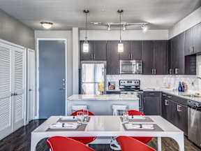 a kitchen with dark wood cabinets and white countertops and a white dining table with red chairs at Republic at Alamo Heights, San Antonio, TX 78209