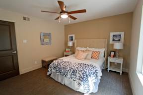 A bedroom with a bed, nightstand, and a ceiling fan.