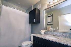 a bathroom with a white toilet next to a sink with a mirror and a shower curtain at Republic at Alamo Heights, Texas, 78209