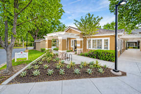 A well-maintained garden in front of a house with a sign that reads "The Enclave.".