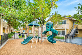 A playground with a green slide and a green canopy.