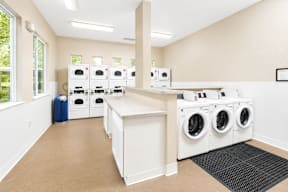 A laundry room with a row of washing machines.