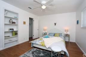 Spacious bedroom with white bedding and hardwood floors at Creekline Apartments, Austin, 78757