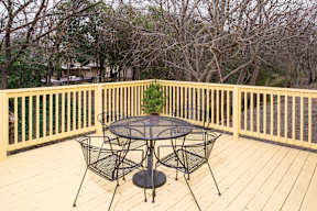 Outdoor deck with seating and wooden railing at Creekline Apartments, Austin, 78757