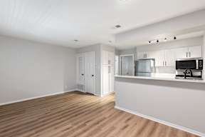 A kitchen with white cabinets and a wooden floor.