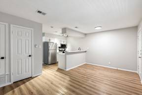 A kitchen with white cabinets and a wooden floor.