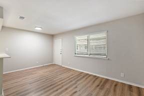 A room with wooden flooring and a window with blinds.