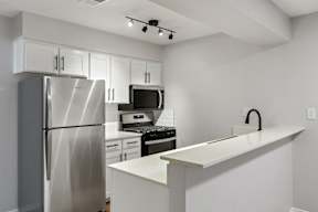 A kitchen with a refrigerator, microwave, oven, and a counter.