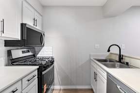 A kitchen with white cabinets and black appliances.