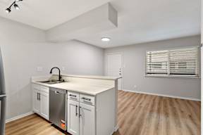 A kitchen with white cabinets and a wooden floor.