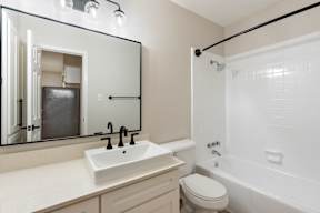 A white sink with a black faucet is in front of a mirror in a bathroom.