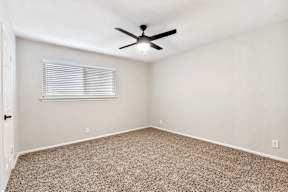 A room with a ceiling fan and carpeted floor.