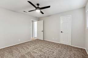 A room with a ceiling fan and carpeted floor.