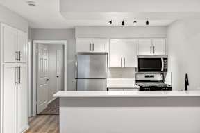 A modern kitchen with white cabinets and appliances.