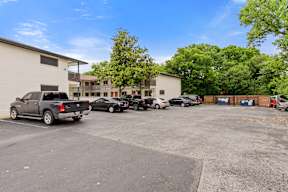 A parking lot with several cars and a building in the background.