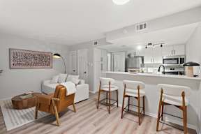 A modern kitchen with white cabinets and a white island with bar stools.