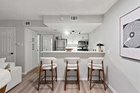 A kitchen with white cabinets and a white fridge with a bar area in front.
