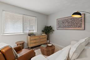 A living room with a brown leather chair, a white couch, and a wooden side table.