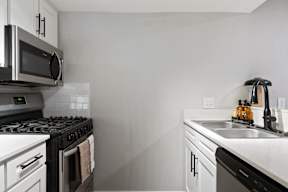 A modern kitchen with a black stove top and white cabinets.