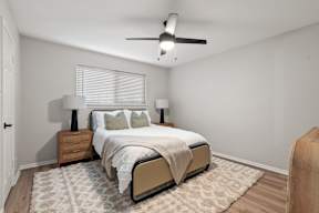 A bedroom with a bed, two lamps, and a ceiling fan.