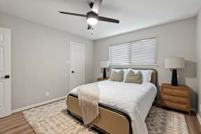 A bedroom with a bed, nightstand, and ceiling fan.