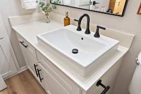 A white sink with a black faucet and a black soap dish.