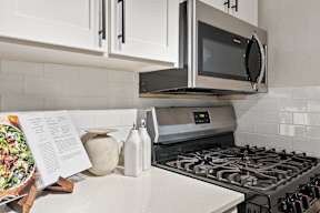 A modern kitchen with a stove, microwave, and white cabinets.