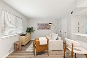 A bedroom with a bed, chair, and a plant.
