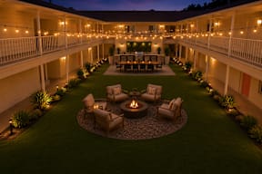 A courtyard with a fire pit surrounded by chairs and plants.