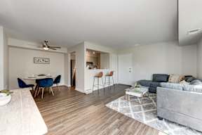 A living room with a grey couch and a dining table with chairs.