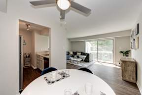 A modern dining room with a white table and a ceiling fan.