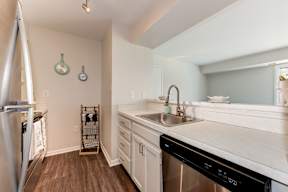 A kitchen with a black dishwasher and white countertops.