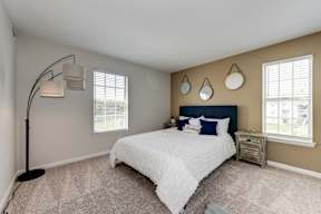 A bedroom with a large bed and a floor lamp.