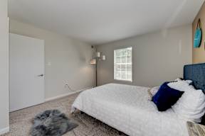 A bedroom with a white bed and a grey furry rug.