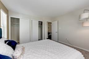 A bedroom with a bed, pillows, and a white carpet.