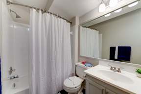 A white bathroom with a toilet, sink, and shower curtain.