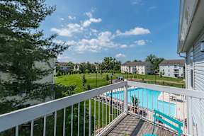 A view from a balcony overlooking a pool and apartment buildings.