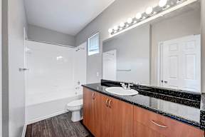 A bathroom with a sink, toilet, and mirror.
