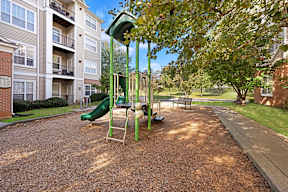 A playground with a green slide and a yellow swing set.