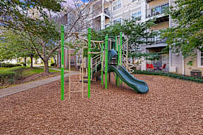 A playground with a green slide and a brown surface.