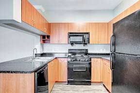 A kitchen with black countertops and wooden cabinets.