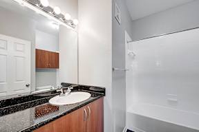 A bathroom with a sink, mirror, and bathtub.