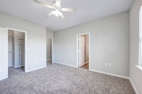 A room with a ceiling fan and carpeted floor.