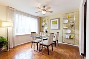 A dining room with a table set for two and a ceiling fan.
