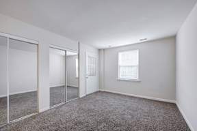 A room with a carpeted floor and a window.