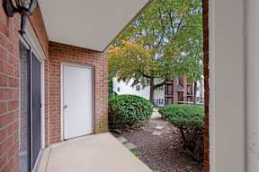A white door is on the left side of a brick building.
