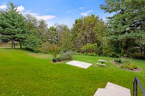 A backyard with a green lawn and trees.