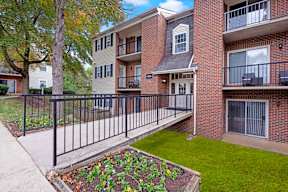 A brick building with a balcony and a small garden in front.