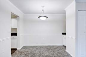 A white room with a grey carpet and a hanging light fixture.