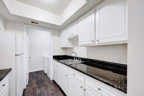 A kitchen with white cabinets and a black counter top.